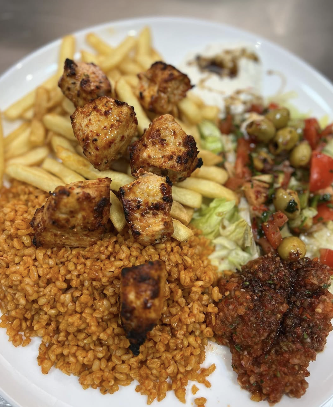 Brochette de poulet grillé au feu de bois avec boulgour, frites et ezme