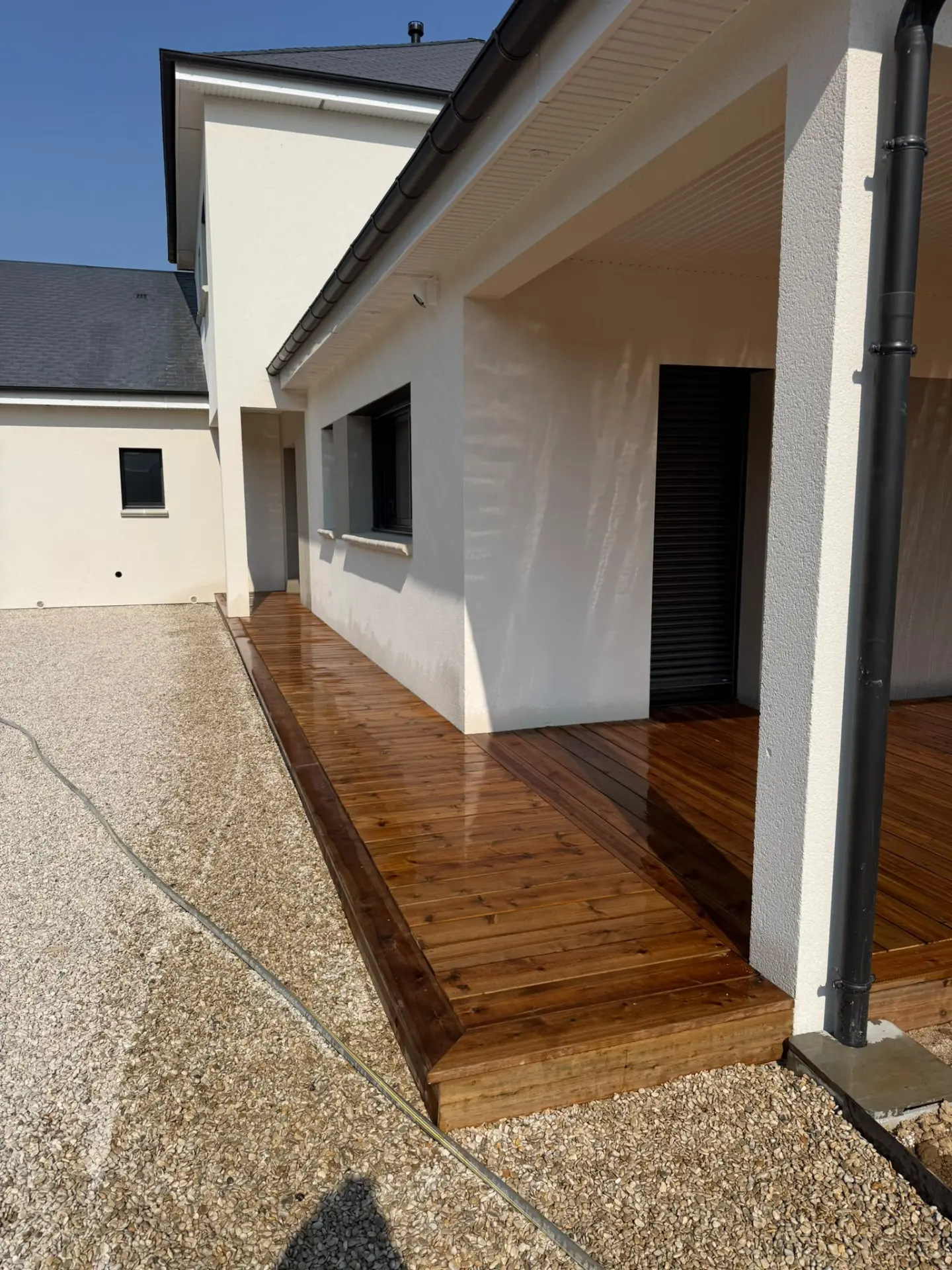 Terrasse bois couverte longeant une maison neuve