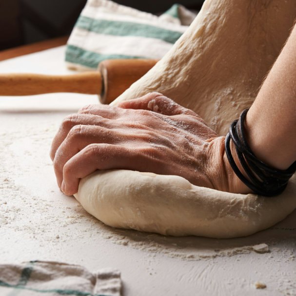Pâte à pizza travaillée à la main, farine et torchon rayé