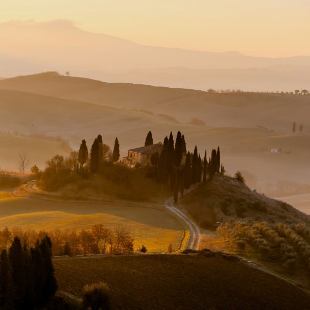 Collines italiennes au coucher du soleil, cyprès et ferme
