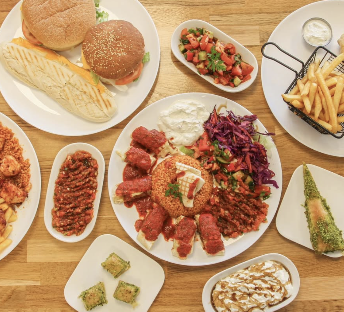 Table garnie de burgers, panini, mezze, salades et baklava chez Gold'n Grill