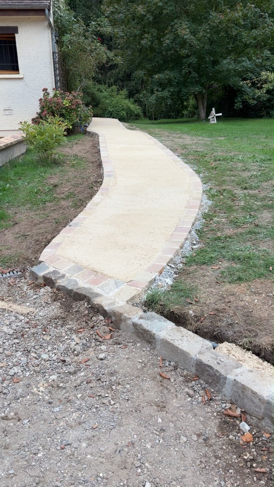 Allée pavée en pierre naturelle bordée d'une bordure béton