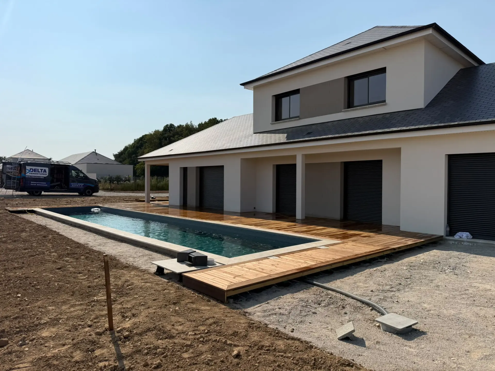 Terrasse bois autour d'une piscine devant une maison contemporaine